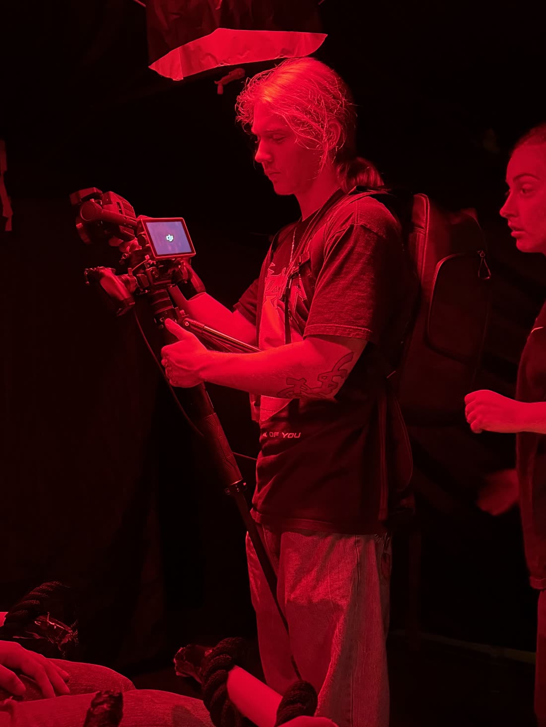 Fuller filming with a camera rig under red light on a shoot