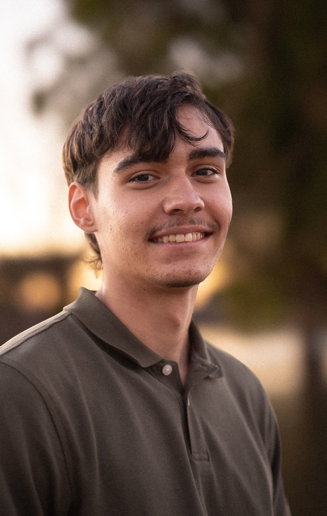 Thomas, smiling, in an outdoor portrait at golden hour